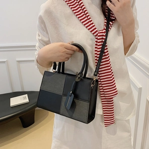 Fashionable black and grey color-block tote bag with adjustable strap and designer tag