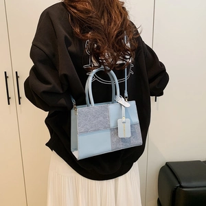 Blue and grey patchwork tote bag with cylindrical handles and adjustable shoulder strap