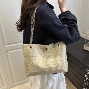 Beige woven tote bag with gold chain strap and deer charm shown from a side view