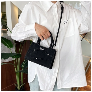 Détail du sac cabas en velours noir avec nœuds en perles et bandoulière amovible
