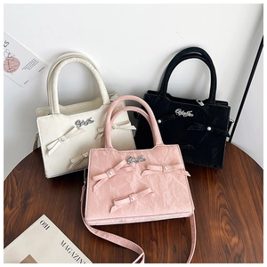 Vue détaillée de trois sacs cabas en cuir plissé avec nœuds et perles sur table en bois