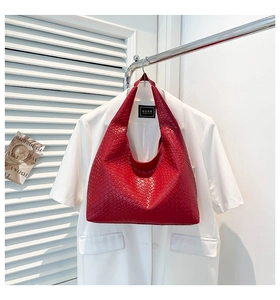Close-up of red intrecciato woven tote bag with wide shoulder strap on display