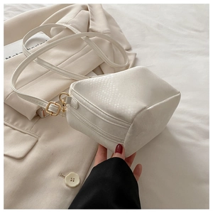 Detail of white faux leather crossbody bag showing fine snake skin texture and gold buckle