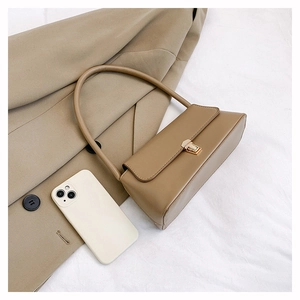 Détail du sac baguette en cuir kaki montrant le fermoir doré et un smartphone de taille