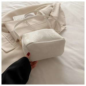 Detailed view of white snakeskin pattern leather bag with golden metal buckle and strap