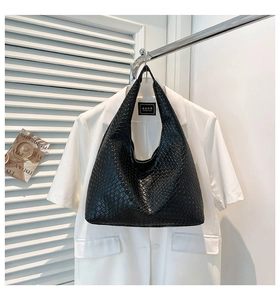 Detail of woven leather texture on a black hobo bag with a minimalist background