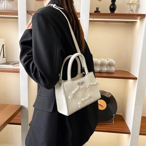 Sac à main blanc élégant avec nœuds en perles porté par un mannequin dans un studio