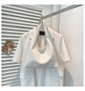 Close-up of white woven texture and shoulder strap detail on a fashion hobo bag
