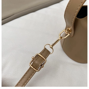 Detail of golden metal buckle and smooth khaki leather stitching on the shoulder bag