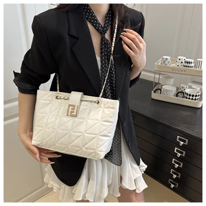 Detail of white quilted tote bag with gold geometric buckle and chain strap