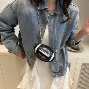 Schwarze Rugby-Umhängetasche mit Goldkette an Model in Jeansjacke und weißem Kleid gezeigt