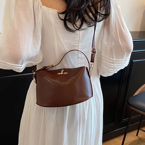 Elegant dark brown leather handbag with gold metal clasp worn with a white dress
