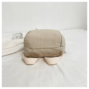 Close-up of beige nylon backpack fabric texture and wide shoulder strap on white cloth