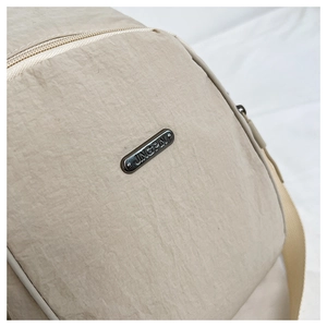 Close-up of beige nylon backpack fabric texture with silver metal brand nameplate