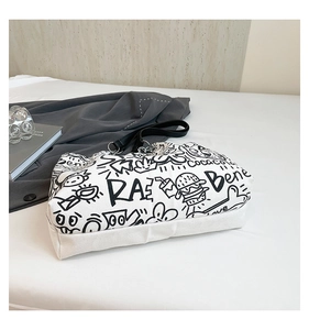 Détail du sac cabas en toile blanche avec imprimés graffiti noirs et boucle en métal argent