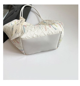 Detail of white tote bag with colorful embroidery and fashion branded leather patch