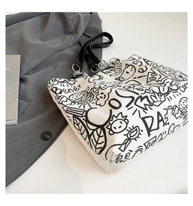 Détail du sac cabas en toile blanche avec imprimé graffiti noir et anses en cuir noir