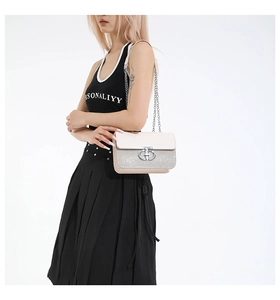Detail of silver chain strap and sequin patchwork on a stylish beige women's flap bag