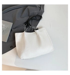 Détail du cabas en toile blanche avec bandoulière en cuir noir et chaîne argentée