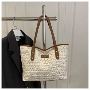 Detailed view of the lace woven texture and leather straps on the cream tote bag