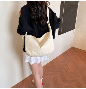 Rückansicht eines Modells mit einer großen, cremeweißen Plissee-Stofftasche für Alltag