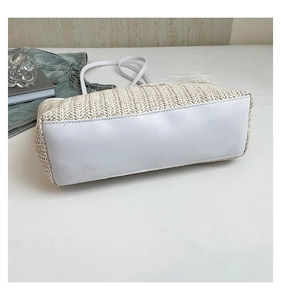 Detail view of woven straw tote bag with white faux leather base and fine stitching