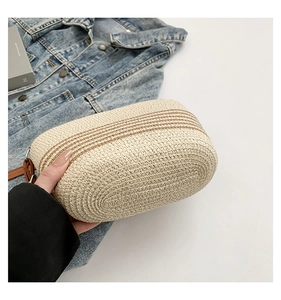 Detail shot of beige woven shoulder bag with brown stripes and adjustable leather strap