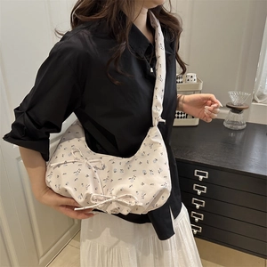 Sac bandoulière floral avec nœuds et large bandoulière porté par un mannequin