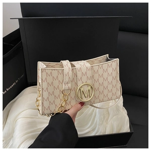 Primer plano de bolso beige con estampado de monograma y cierre dorado en caja de regalo