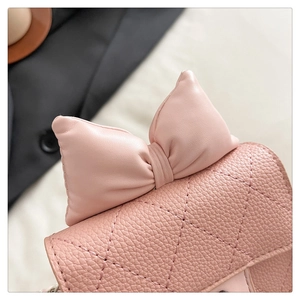 Close-up of pink mini bag featuring quilted diamond pattern and a large leather bow detail