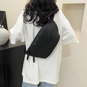 Sac de poitrine noir minimaliste avec bandoulière réglable porté par un mannequin
