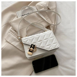 Detailed view of white quilted faux leather bag with elegant gold lock and chain