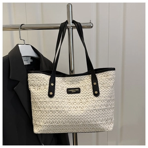 Detail of white crochet tote bag with black leather straps and metallic rivets