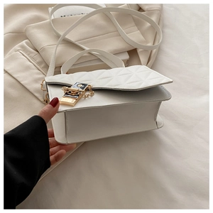 Detailed macro view of the white quilted crossbody bag with gold-tone hardware and chain