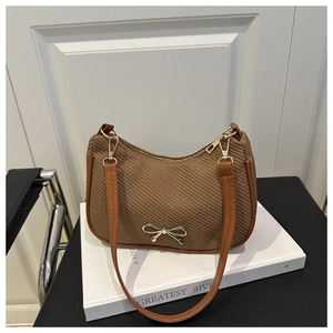 Detail of brown woven shoulder bag featuring a golden bow buckle and fine texture