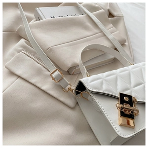 Detail of white quilted crossbody bag with golden twist lock and elegant metal chain strap
