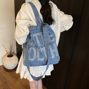 Vintage washed blue denim tote bag with frayed 3D letters and wide shoulder strap
