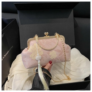 Détail d'un sac de soirée rose à fleurs avec cadre doré et long gland blanc élégant