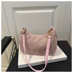 Detailed macro of pink woven texture underarm bag with gold metal bow charm accent