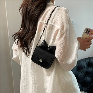 Chic quilted mini chain bag with leather bow and floral clasp shown on shoulder