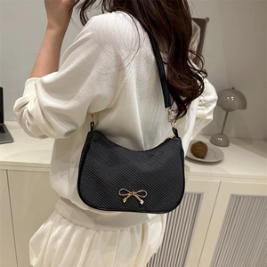 Fashionable black half-moon shoulder bag with golden bow accent and diagonal texture