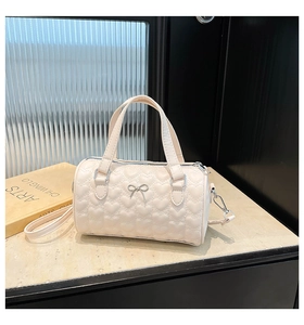 Détail du sac cylindrique crème avec gaufrage coeurs 3D et boucle noeud argenté