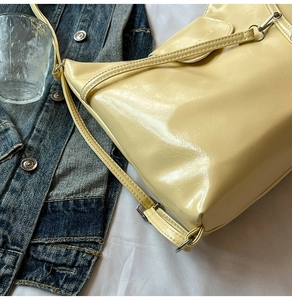 Detail of light yellow glossy patent leather shoulder bag with natural wrinkled texture