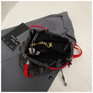 Macro view of distressed denim tote with frayed edges and vibrant red woven straps