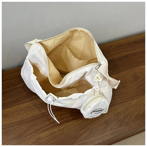 Detail of white nylon shoulder bag interior with beige lining and a fashion coin purse