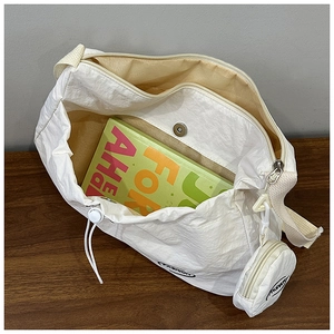 Detail showing white nylon crossbody bag with mini round pouch and spacious interior