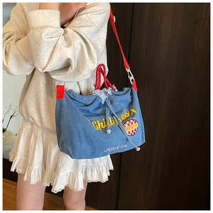 Detail of blue denim tote bag featuring red rope handles and yellow Chillies embroidery