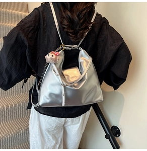 Detail of silver metallic backpack with brand logo and cute plush charm on a staircase