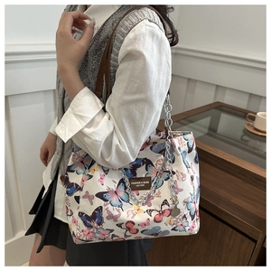 Detail of white tote bag with colorful butterfly prints and brown leather strap