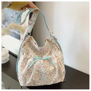 Detailed view of floral canvas bag with blue plaid bow and adjustable strap